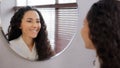 Young calm attractive woman in bathrobe stands in bathroom looks in mirror admiring reflection enjoy healthy skin after
