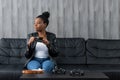 Young calm black woman relaxing sitting on black sofa in modern living room, happy african american woman relaxing Royalty Free Stock Photo