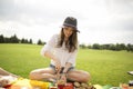 Young calm peaceful woman in park outside at sunny day. Alone sit and prepare food for picnic. Blanket full of delicious Royalty Free Stock Photo