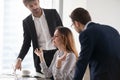 Young calm woman meditating in workplace, ignoring colleagues.