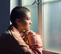 Young cancer patient standing in front of hospital window