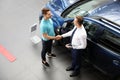 Young car salesman shaking hands with client