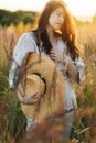 Young carefree female in rustic linen cloth relaxing in summer meadow. Stylish boho woman with straw hat posing among wild grasses Royalty Free Stock Photo