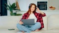 Young carefree girl with laptop in lotus pose listens loud favorite music enjoys song audio track teenage redhead Royalty Free Stock Photo
