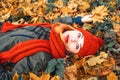 Young carefree woman with autumn yellow leaves in hand in orange knitted hat and scarf. Happy woman with red hair and black eyes Royalty Free Stock Photo