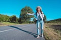 Young carefree woman with backpack travelling by car. Road trip adventure. Woman stopping car with thumbs up