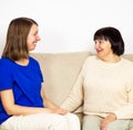 Young caregiver helping senior woman at home. Caring nurse hugging her middle aged female patient. Royalty Free Stock Photo