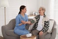 Young caregiver measuring blood pressure of senior woman in room. Home health care service Royalty Free Stock Photo