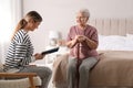 Young caregiver reading book to senior woman. Home care service Royalty Free Stock Photo