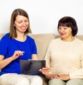 Young caregiver showing a precsription or document and helping senior woman at home.