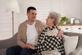Young caregiver talking to senior woman in living room. Home health care service Royalty Free Stock Photo