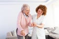 Young carer supporting senior disabled woman with walking stick. Portrait of happy female caregiver and senior woman walking Royalty Free Stock Photo