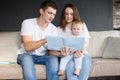 Young caring father reads a book to his child, child and mother listen while sitting on the sofa at home.Family holidays Royalty Free Stock Photo