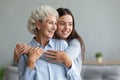 Young caring grand daughter hugs loving elderly grandmother