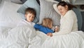 Young caring and loving mother lying next to her two sons sleeping in bed at morning. Concept of family happiness, relaxing at Royalty Free Stock Photo