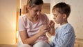 Young caring mother cutting fingernails to her son wearing pajamas in bedroom Parenting, child hygiene and healthcare, going to Royalty Free Stock Photo