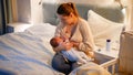 Young caring mother feeding her newborn baby son in dark room at night. Concept of healthy and natural baby nutrition Royalty Free Stock Photo