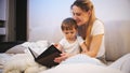 Young caring mother in pajamas reading bedtime story to her toddler boy Royalty Free Stock Photo