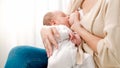 Young caring mother sitting on bed and feeding her newborn baby boy with breast milk. Concept of healthy and natural Royalty Free Stock Photo