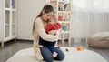 Young caring mother soothing and comforting her upset crying baby boy on carpet in living room Royalty Free Stock Photo