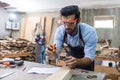 young carpenter caucasian man using measuring tape looking wood size at workspace. craftsman profession in wood factory