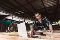 Young carpenter caucasoid man worker. he looking designs in laptop computer at own workspace.