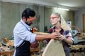 young carpenter man and women using measuring tape looking wood size at workspace. craftsman profession in wood factory Royalty Free Stock Photo