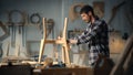 Young Carpenter Reading Blueprints and Starting to Assemble Parts of a Wooden Chair with a Rubber