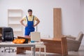 Young male carpenter repairing desk in the office