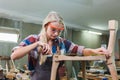 Young carpenter women using measuring tape looking wood size at workspace. craftsman profession in wood factory Royalty Free Stock Photo