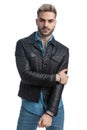 Young casual biker guy in leather jacket holding arms in fashion pose