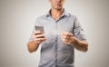 Young casual business man holding phone and business card possibly making contact