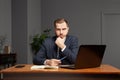 Young casual businessman or entrepreneur thinking and using laptop in office Royalty Free Stock Photo