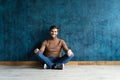 Young casual fashion man sitting on the floor  on dark blue background. Royalty Free Stock Photo