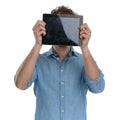 Young casual guy hiding behind tablet Royalty Free Stock Photo