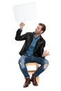 Seated man holding speech bubble sideways mystified Royalty Free Stock Photo