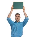 Young casual man holding a board overhead