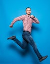 Young casual man jumping for joy on blue background Royalty Free Stock Photo