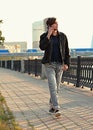 Young casual man walking on the street and talking on mobile phone on city center background Royalty Free Stock Photo