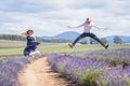 Young casual trendy boy and girl jumping at lavender field. Blue cloud summer daytime. Royalty Free Stock Photo