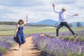 Young casual trendy boy and girl jumping at lavender field. Blue cloud summer daytime. Royalty Free Stock Photo