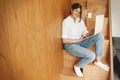 Young casual woman shopping online or working online from home and smiling. Happy stylish girl using laptop, sitting on wooden Royalty Free Stock Photo