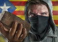 Young Catalan man as ultra and radical separatist holding brick protesting in face mask holding brick threatening at nationalistic