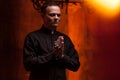 Young Catholic Praying priest. Portrait of priest Next to the candles prays with his hands Royalty Free Stock Photo