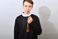 A young Catholic priest holds a prayer beads in his hand