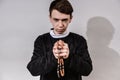 A young Catholic priest holds a rosary in his hand in prayer. The concept of driving out the devil and evil spirits Royalty Free Stock Photo