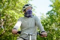 Young cauacasian man in helmet cycling outdoor in forest closing his face with scarf