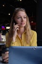 young cauasian pretty woman at coffee shop with laptop, calling by smartphone