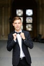 Young caucaisian man standing and posing, wearing black suit and bow tie. Royalty Free Stock Photo