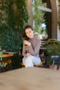 Young caucaisian woman posing at street cafe, closed laptop computer on table. Royalty Free Stock Photo